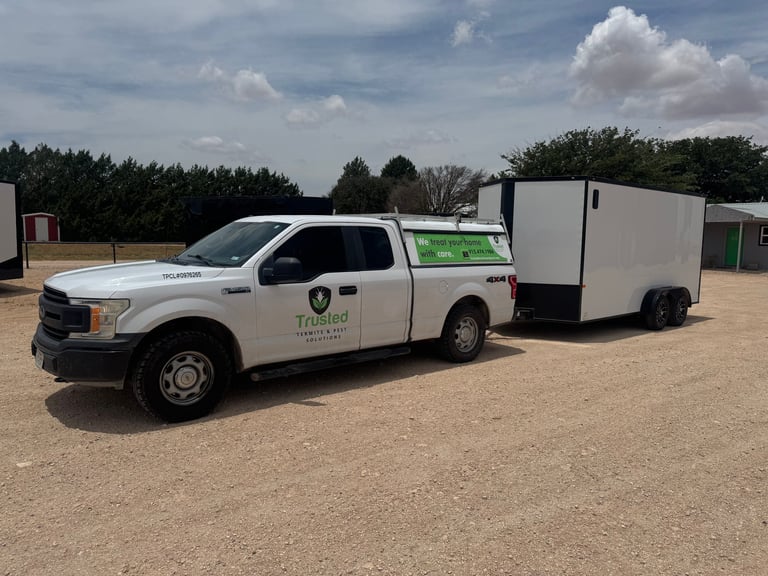 White pickup truck with green and white branding towing a white enclosed cargo trailer in a paved lot